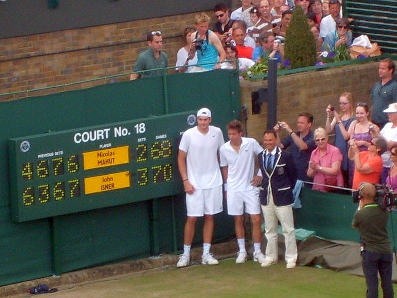 The two players and the umpire beside the scoreboard showing 70-68